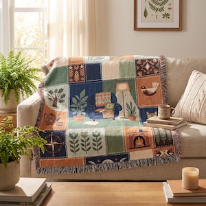 Pode incluir: Uma manta tecida com um design de patchwork de várias ilustrações, incluindo uma poltrona azul, um candeeiro de pé, plantas em vasos, uma lareira, uma bússola, um pássaro e uma árvore em tons de azul, verde, laranja e creme com franjas.