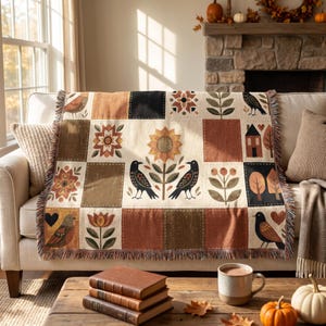 Könnte beinhalten: Eine gewebte Wohndecke mit Patchwork-Design und abwechselnden Quadraten in Creme, Braun und Schwarz. Das Muster zeigt Illustrationen von Sonnenblumen, Vögeln, Häusern, Herzen und Blumenmotiven in den Farben Orange, Grün und Braun.