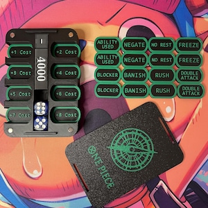 May include: A black plastic game tracker with green accents, featuring slots labelled +1 Cost through +8 Cost, a central column displaying 4000, and two blue dice. Includes sixteen rectangular green and black status markers and a black One Piece card.
