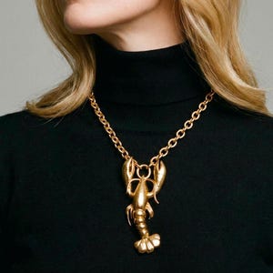 Surrealistiskt guldfärgat hummerhängehalsband, avantgardistiska smycken i statement-stil, överdimensionerad anatomisk skaldjursberlock, guldfärgat statement-smycke