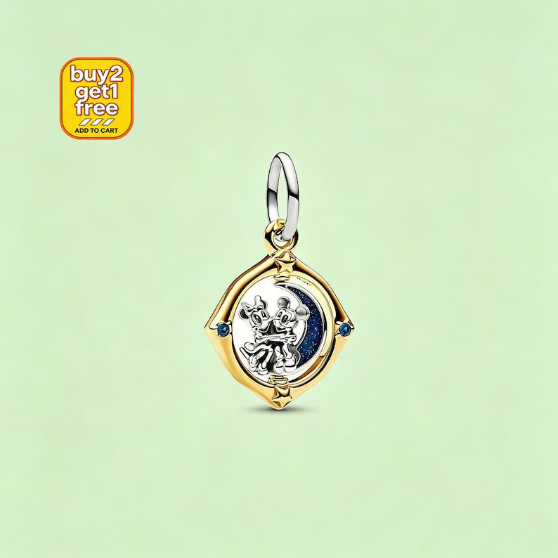 May include: A gold-toned charm pendant featuring Mickey and Minnie Mouse embracing in front of a crescent moon. The charm has a gold frame with blue accents and a silver loop for attachment. The charm is a Disney-themed jewelry item.