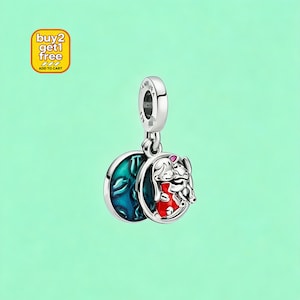 Puede incluir: Un charm de plata con un personaje de dibujos animados con un atuendo rojo y un fondo azul. El charm tiene un dise&ntilde;o circular y est&aacute; suspendido de un lazo plateado. La imagen tambi&eacute;n incluye un cuadrado amarillo con el texto "buy 2 get 1 free" y "add to cart".