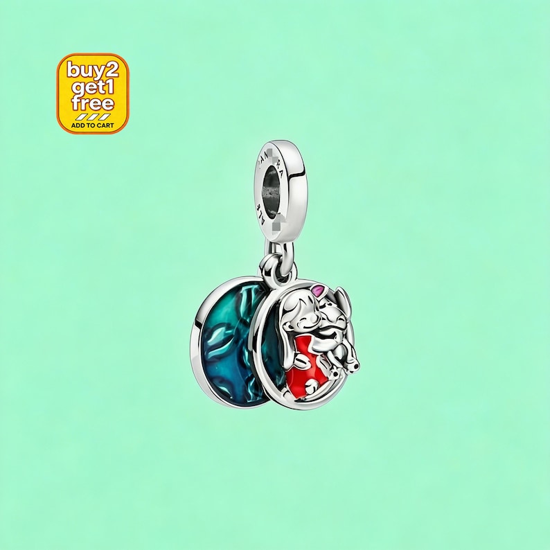 Puede incluir: Un charm de plata con un personaje de dibujos animados con un atuendo rojo y un fondo azul. El charm tiene un dise&ntilde;o circular y est&aacute; suspendido de un lazo plateado. La imagen tambi&eacute;n incluye un cuadrado amarillo con el texto "buy 2 get 1 free" y "add to cart".
