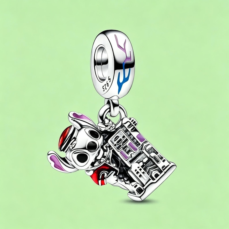 May include: A silver charm with a cartoon character and a purple and white building. The charm has a loop at the top with blue and purple accents. The cartoon character is wearing a red hat and outfit.