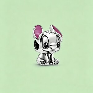 May include: A silver charm depicting the character Stitch from Lilo & Stitch. The charm features Stitch's signature large ears with pink accents, big black eyes, and a small, smiling mouth. The charm is set against a light green background.
