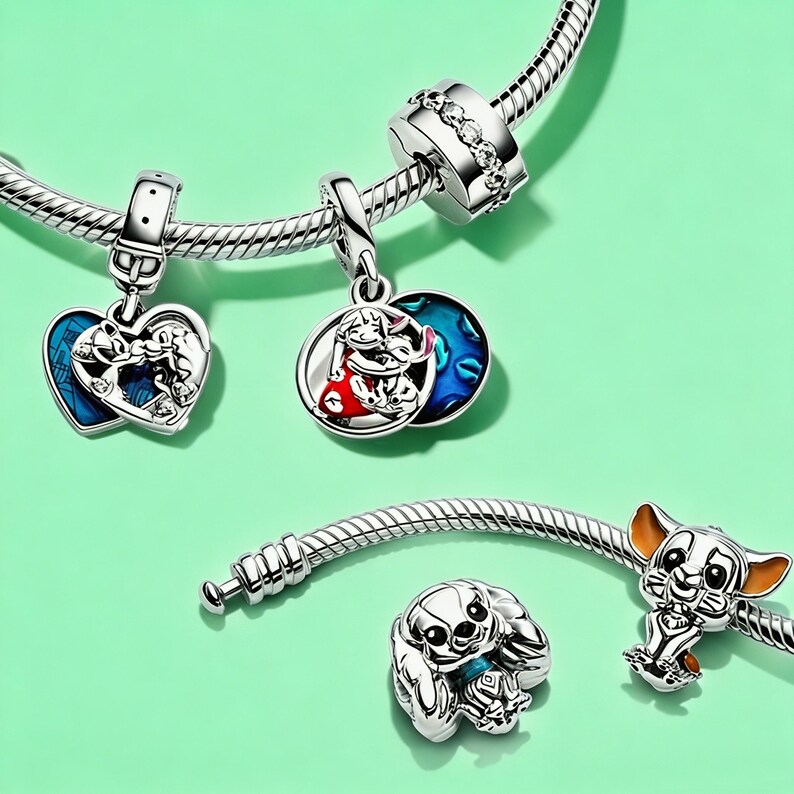 Puede incluir: Pulsera de abalorios de plata con varios abalorios tem&aacute;ticos de Disney. Los abalorios incluyen un abalorio en forma de coraz&oacute;n con un fondo de esmalte azul, un abalorio redondo con esmalte rojo y azul y dos abalorios de personajes. Sobre un fondo verde claro.