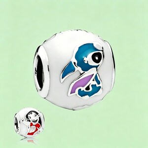 May include: A white charm bead with a blue and purple cartoon character design. The charm has a silver-colored border and a hole for threading onto a bracelet. A smaller charm with a cartoon character is also visible.