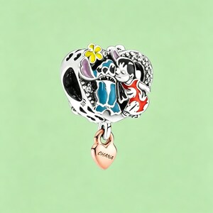 May include: A silver charm featuring a heart-shaped design with a black and white pattern, and a rose gold heart pendant. The charm depicts a blue alien and a girl in a red dress. The rose gold heart pendant says "Ohana".