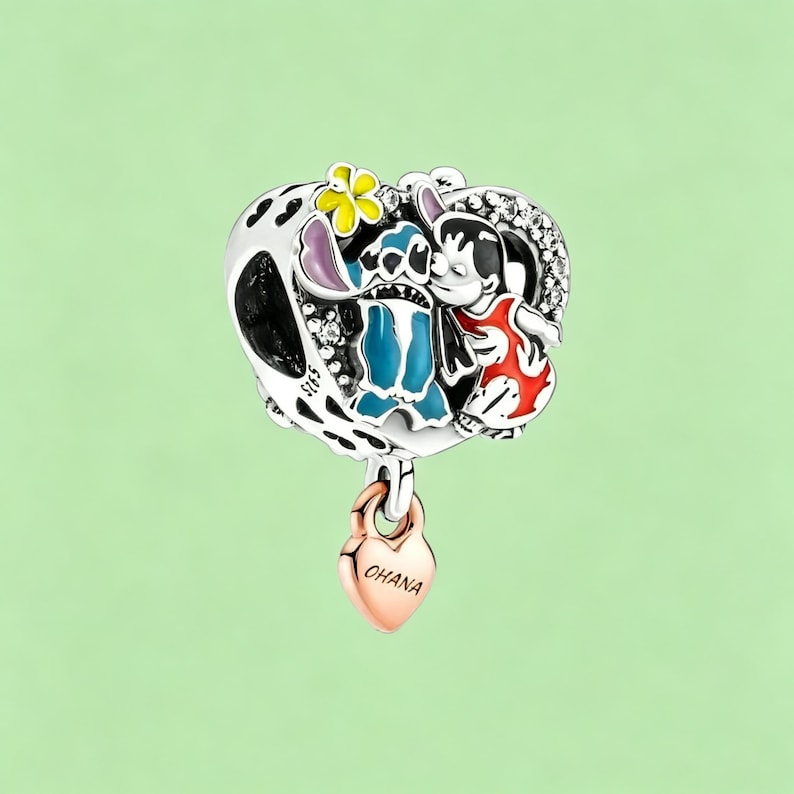 May include: A silver charm featuring a heart-shaped design with a black and white pattern, and a rose gold heart pendant. The charm depicts a blue alien and a girl in a red dress. The rose gold heart pendant says "Ohana".