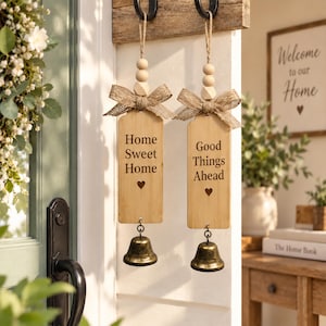 May include: Two rectangular wooden hanging signs with jute twine loops and wooden beads. Each sign features a burlap bow, a metal bell at the bottom, and engraved text. One sign reads Home Sweet Home, and the other reads Good Things Ahead.