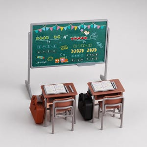 Peut inclure: Une scène de classe miniature avec un tableau vert affichant des dessins et des problèmes mathématiques. Deux bureaux avec des livres ouverts et des trousses sont devant le tableau. Une mallette marron et une noire sont placées près des bureaux.