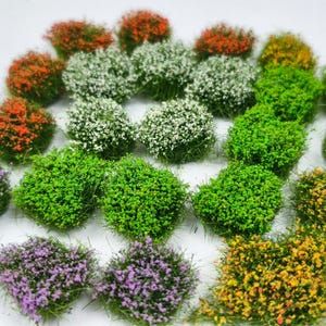 Peut inclure: Une collection de grappes d'arbustes artificiels miniatures dans diverses couleurs, notamment vert vif, orange, blanc, violet et jaune. Ces petits éléments de feuillage texturés présentent des bases herbeuses denses avec de minuscules accents floraux.