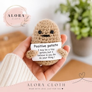 May include: A small, tan, crocheted potato figure with black bead eyes and a stitched mouth. It holds a white rectangular card that reads: Positive potato. I may be a tiny potato, but I believe in you. Go do your thing!