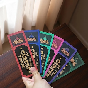 May include: A set of rectangular paper tickets in red, blue, green, pink, and purple, each featuring a black center panel with gold text reading The Freak Circus Ticket, a circus tent graphic, and small star and spade symbols at the top.