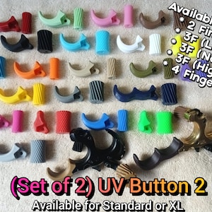 May include: A collection of multi-colored archery release aid components including curved finger pieces and textured cylindrical buttons. Text reads: Available for: 2 Finger, 3F (Low), 3F (Normal), 3F (High), 4 Finger, (Set of 2) UV Button 2, Available for Standard or XL.