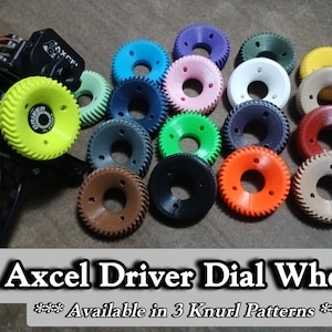 May include: A selection of multi-coloured Axcels Driver Dial Wheels. The wheels are in various colours including yellow, blue, pink, white, green, black, orange, and brown. The text "Axcels Driver Dial Wheel" is displayed at the bottom of the image.