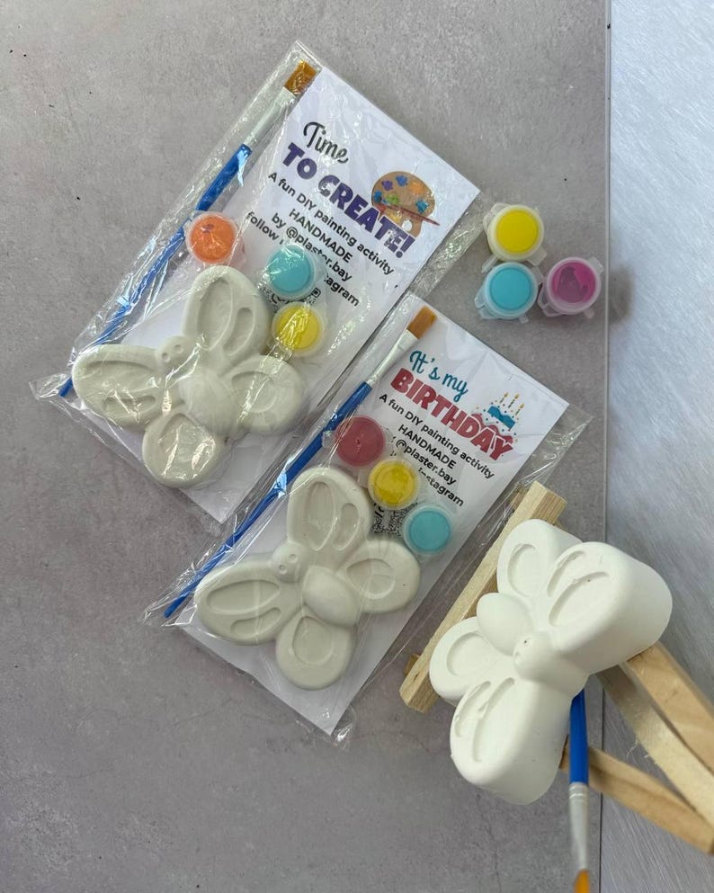 May include: Two DIY plaster butterfly painting kits. Each kit includes a white butterfly figure, paint pots in various colors, and a paintbrush. One kit has the text "Time TO CREATE!" and the other says "It's my BIRTHDAY".