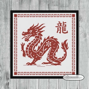 May include: Cross-stitch design featuring a red dragon with the Chinese character for "dragon" in the upper right corner. The dragon is surrounded by a decorative border and set against a white background. The design is framed in a black square.