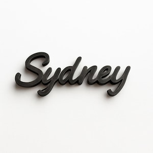May include: The word "Sydney" is presented in a black, flowing script against a white backdrop. The letters are joined, with a subtle shadow adding depth. The design is clean and stylish, suitable for various applications.