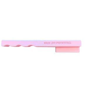 May include: A light pink, elongated, rectangular plastic object with a wavy edge on one side and a protruding rectangular tab on the other. The text RKR 3D PRINTING is embossed in a horizontal line across the center of the flat surface.