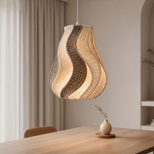 May include: A woven pendant light fixture with a wavy design, featuring alternating sections of light beige, dark brown, and off-white. The light hangs above a wooden dining table, illuminating the space with a warm glow. The fixture is a decorative element.