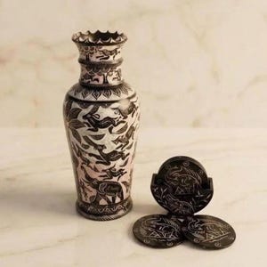 Könnte beinhalten: Eine dekorative Vase und passende Untersetzer. Die Vase ist weiß mit schwarzen, geätzten Designs von Tieren und Blättern. Die Untersetzer sind schwarz mit ähnlichen geätzten Designs. Das Set ist für die Inneneinrichtung konzipiert.
