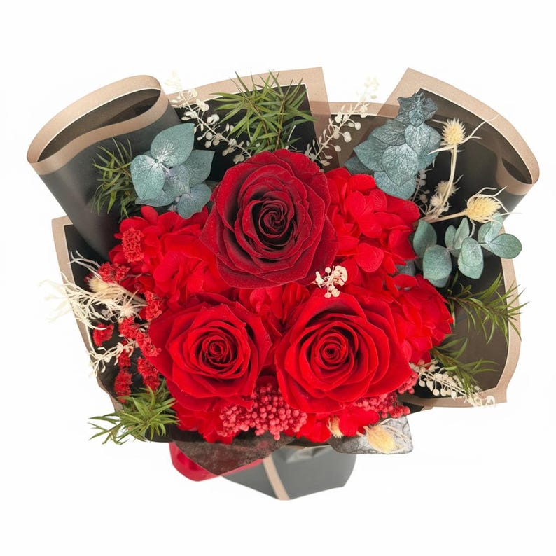 Puede incluir: Un ramo de vibrantes rosas rojas y otras flores rojas, acentuado con follaje verde y gris. El arreglo est&aacute; envuelto en papel negro y marr&oacute;n, creando un contraste llamativo. Las flores se presentan en un jarr&oacute;n gris oscuro.