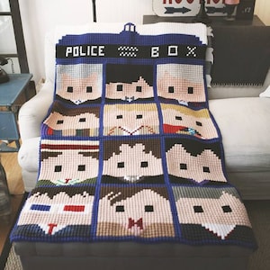 May include: A blue and white crocheted blanket featuring the faces of the Doctors from the TV show Doctor Who. The blanket is labeled "Police Box" and features the iconic TARDIS design.