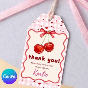 May include: A gift tag with a pink gingham pattern and a red border. The tag features a cherry illustration and the words "thank you!" and "Karlie". A pink ribbon is tied to the tag.