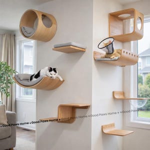 Pode incluir: Um conjunto moderno de móveis para gatos em tons de madeira clara, montado numa parede branca. O conjunto inclui várias plataformas, uma cama curva e uma casa cilíndrica para gatos. Um gato está a descansar numa das plataformas. O texto "Good Paws Home" é visível.
