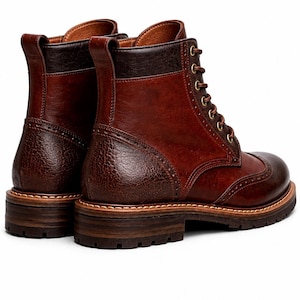 May include: A pair of brown leather boots with a classic wingtip design. The boots feature a textured leather on the heel and a lace-up closure with brass eyelets. The soles are made of a dark brown material.