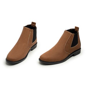 May include: Two brown Chelsea boots with black soles and elastic side panels. The boots have a smooth, matte finish and a classic, ankle-high design. The stitching is visible along the seams.