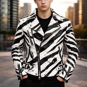 May include: A black and white zebra-striped leather jacket with multiple zippers and a notched collar. The jacket is worn over a black top and paired with black trousers. The overall style is edgy and modern.