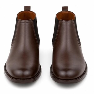 May include: A pair of brown leather Chelsea boots. The boots have a rounded toe, elastic side panels, and a pull tab at the back. The interior is a lighter brown color. The boots are set against a white background.