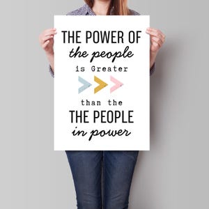 Peut inclure: Une affiche blanche avec du texte noir qui dit "THE POWER OF the people is Greater than the THE PEOPLE in power". Trois flèches colorées pointent vers la droite.