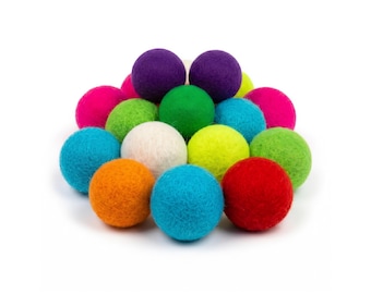 May include: A collection of colorful felt balls in various shades, including purple, green, blue, pink, orange, white, and yellow. The balls are arranged in a pile against a white background. These decorative balls are suitable for crafts.