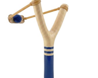 May include: A wooden slingshot with a blue and white painted handle. The slingshot has a natural wood finish on the arms and a blue projectile. The slingshot is designed for recreational use.