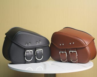 A pair of classic motorcycle side bags—black and brown leather side bags suitable for scooters, cruisers, and other motorcycles.