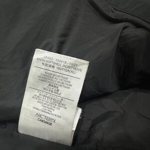 May include: A close-up of a black softshell jacket with a tag. The tag includes the text "KADIN SOFTSHELL JACKET MEN'S" and "MADE IN VIETNAM". The jacket is made in Vietnam.