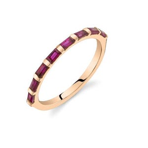 May include: A rose gold ring featuring a band of rectangular, deep pink gemstones. The gemstones are evenly spaced around the ring, creating a continuous pattern. The ring is set against a white background, highlighting its elegant design.