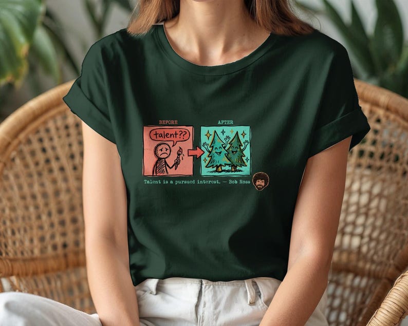 A streetwear-style t-shirt featuring a Y2K cyber-graphic with a portrait of Bob Ross and the quote "Talent is a pursued interest" in bold typography.