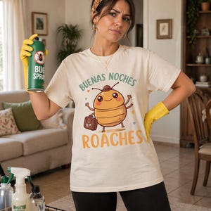 Puede incluir: Una mujer con una camiseta crema con un diseño de cucaracha de dibujos animados y las palabras "Buenas Noches Roaches". Sostiene un bote de spray verde para insectos y usa guantes amarillos. Productos de limpieza en primer plano.