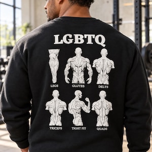 May include: A black long-sleeve sweatshirt featuring a white graphic on the back. The text LGBTQ is at the top, followed by six anatomical illustrations of human muscles labeled Legs, Glutes, Delts, Triceps, Tight Fit, and Quads.