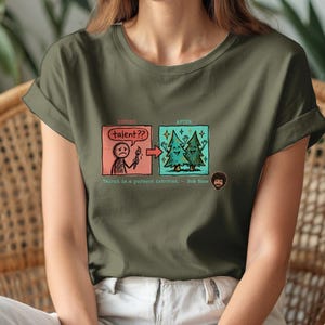A streetwear-style t-shirt featuring a Y2K cyber-graphic with a portrait of Bob Ross and the quote "Talent is a pursued interest" in bold typography.