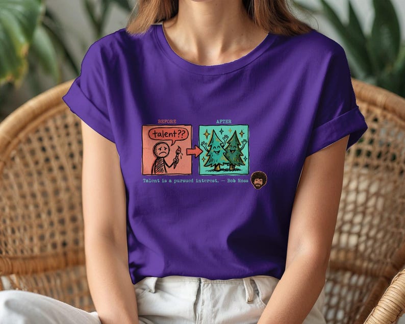 A streetwear-style t-shirt featuring a Y2K cyber-graphic with a portrait of Bob Ross and the quote "Talent is a pursued interest" in bold typography.