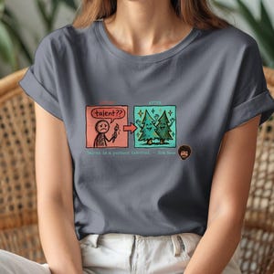 A streetwear-style t-shirt featuring a Y2K cyber-graphic with a portrait of Bob Ross and the quote "Talent is a pursued interest" in bold typography.