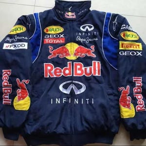 May include: Navy blue Red Bull racing jacket with sponsor logos including Infiniti, Pepe Jeans, and Geox. The jacket features the Red Bull logo prominently on the front and sleeves, with a stand-up collar and blue detailing.