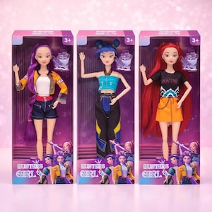 May include: Three fashion dolls in boxes. Each doll has a unique hairstyle and outfit. The dolls are in boxes with the text "Hunters Girl" and the age range "3+". The dolls have purple, blue, and red hair, and wear colorful outfits.
