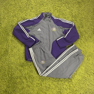 Puede incluir: Una taza de cerámica blanca con un asa negra y el texto "But First, Coffee" en negro, en negrita. La taza está sobre una superficie blanca.