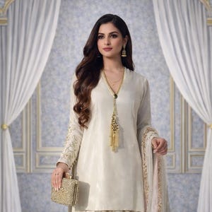 Puede incluir: Conjunto salwar kameez de color marfil con bordado floral. El atuendo incluye una túnica, pantalones sueltos y una dupatta a juego. Un clutch dorado y joyas completan el look. Adecuado para ocasiones especiales.